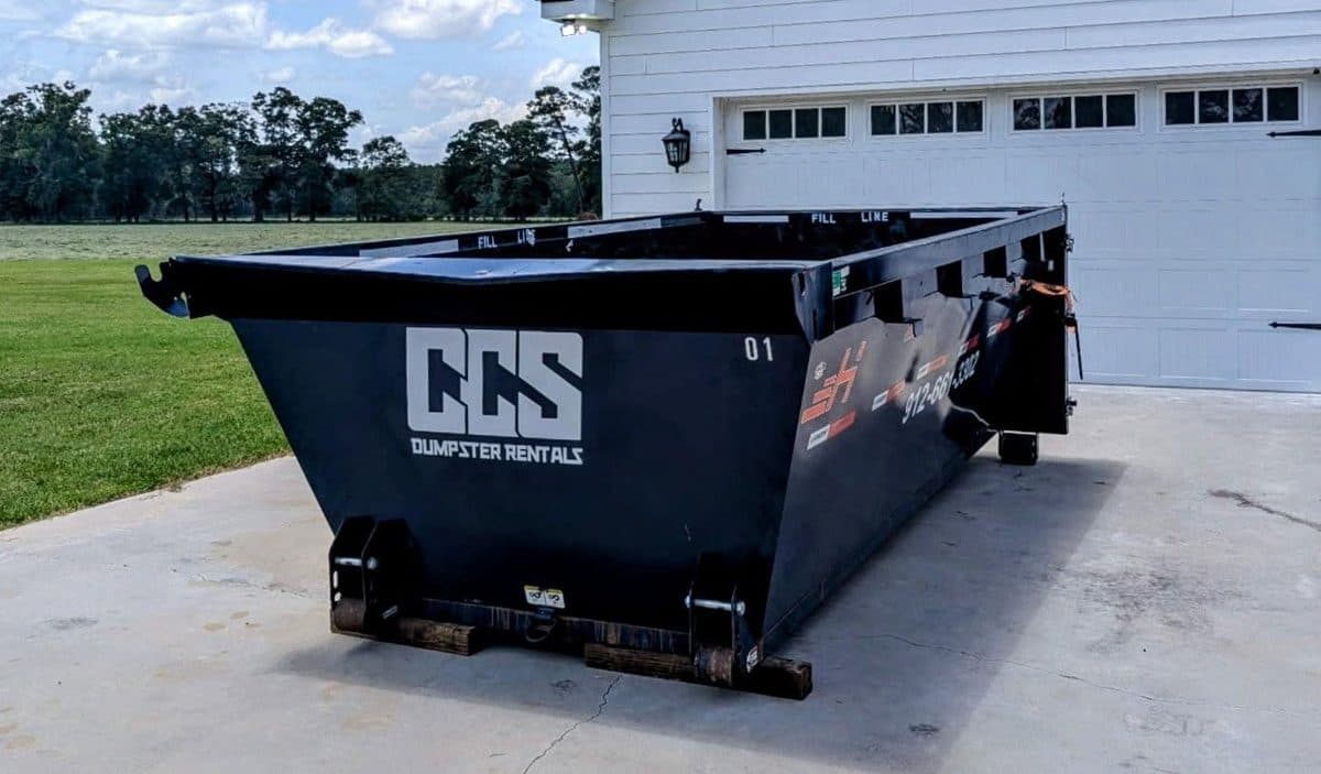 A 14 yard CCS roll-off dumpster sitting level on a residential driveway, ready to load
